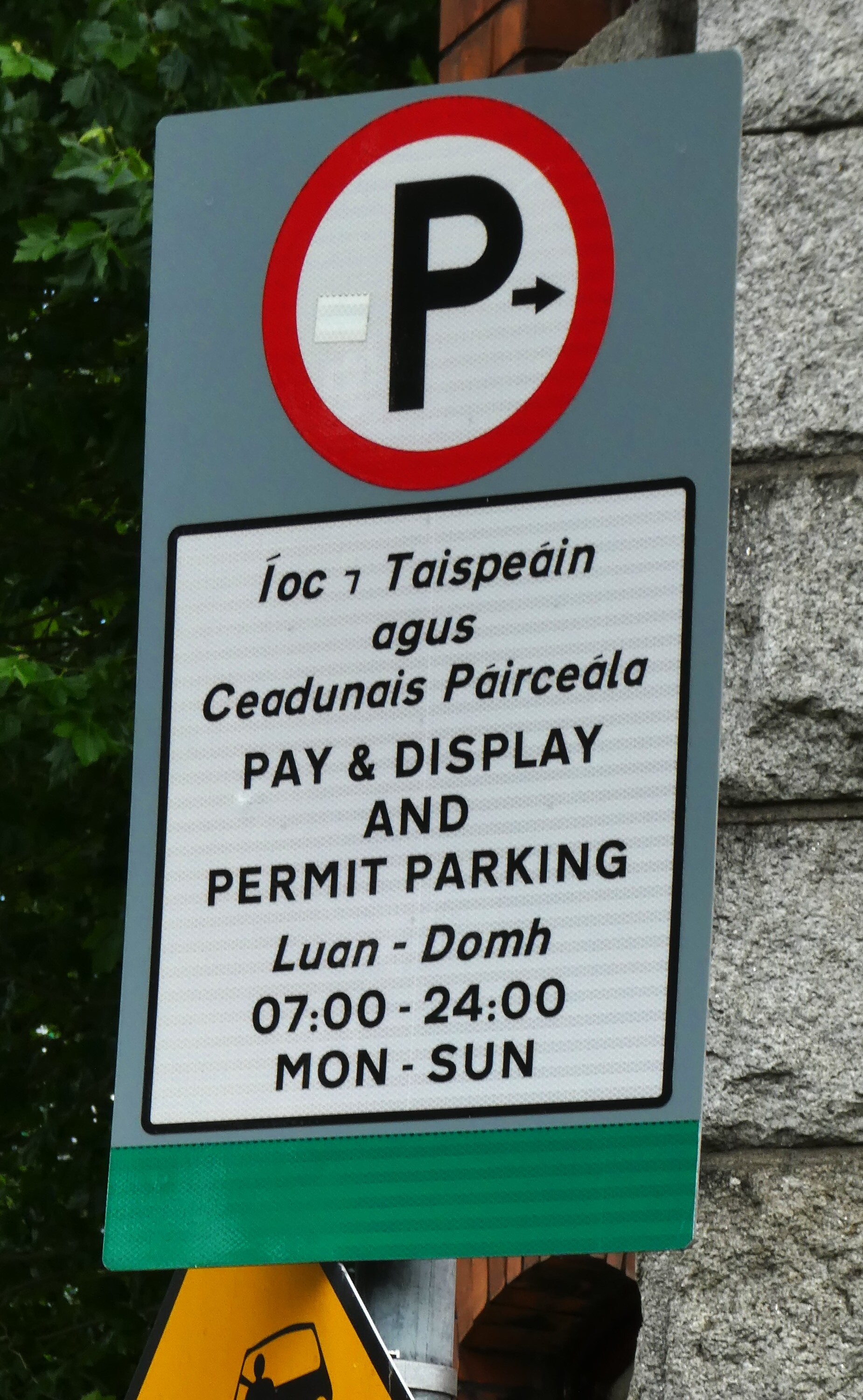 都柏林 Pay and Display 路边停车牌照片，显示 P 箭头、双语 Íoc agus Taispeáin、Pay and Display、周一至周六 07:00-19:00 和周日 14:00-18:00。